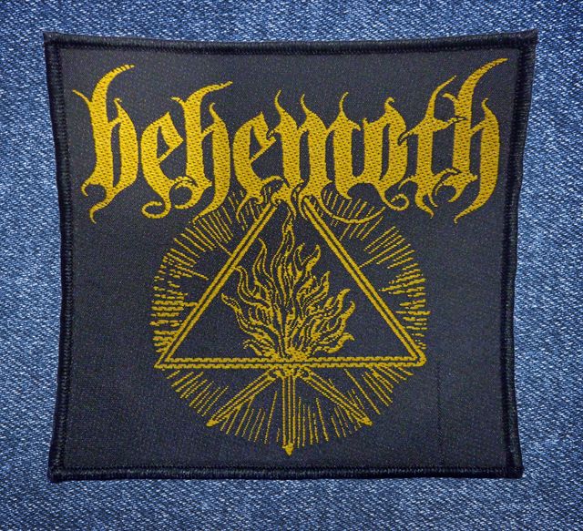 Везана нашивка Behemoth със златен пламък и триъгълник върху черен фон.