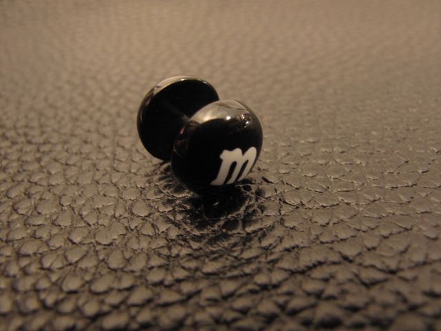 Черна стоманена обеца имитация на флеш с дизайн на бонбон M&Ms и бяла буква m