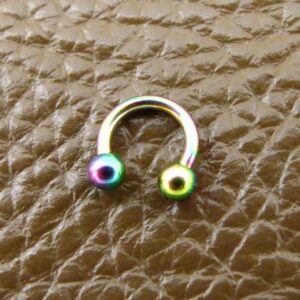Мултицветна обица за септум тип подкова с преливащи цветове Rainbow върху кафява кожа
