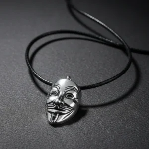 Сребрист медальон маска Гай Фокс (Anonymous), лежащ на кафява кожена повърхност