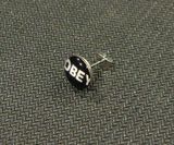 Стоманена обеца за ухо с белия надпис Obey върху черен фон
