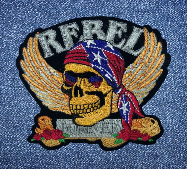 Нашивка за рокерски елек с череп Rebel Forever и златни крила върху деним.
