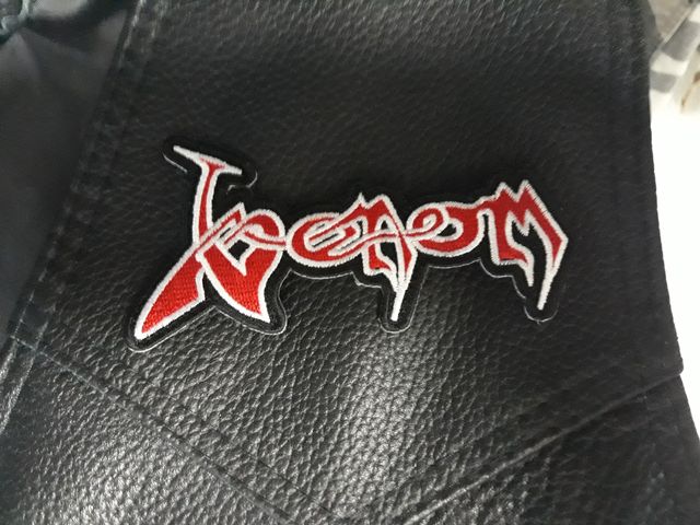 Бродирана нашивка Venom с червено лого и бял контур върху черна кожа.