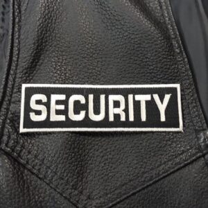 Бродирана нашивка SECURITY с бял надпис върху черна кожа.