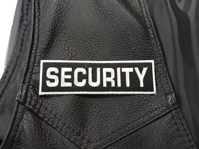 Бродирана нашивка SECURITY с бял надпис върху черна кожа.