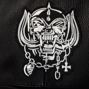 Бродирана нашивка Motorhead Snaggletooth върху черна кожа.
