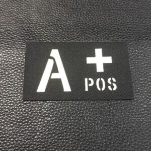 Светеща нашивка с кръвна група A+ POS в бяло върху черен фон.