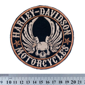 Кръгла бродирана нашивка Harley-Davidson с череп, крила и бежови надписи на черен фон.