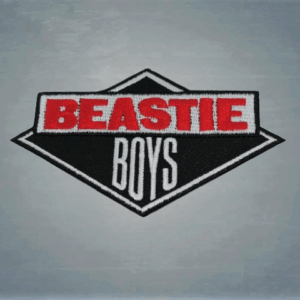 Beastie Boys везана нашивка за дрехи – ромбовидно лого с червен и бял бродиран надпис върху черна основа.