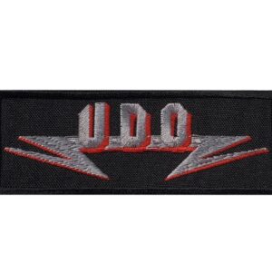 Правоъгълна нашивка U.D.O. със сребристо лого и червени сенки върху черна основа.