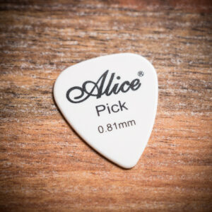 Бяло перце за китара Alice 0.81mm с черно лого Pick върху дървен фон.