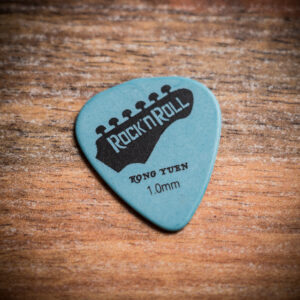 Светлосиньо перце за китара Kong Yuen 1.0mm с черен надпис Rock'n'Roll върху дървен фон