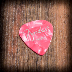 Розово перце за китара Fender 0.71 mm с перлен ефект върху дървена повърхност