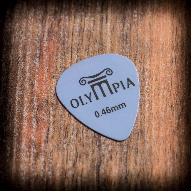 Тънко сиво перце за китара Olympia 0.46 mm върху дървена основа