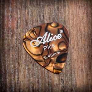 Перце за китара Alice 0.46mm от кафяв целулоид върху дървена повърхност